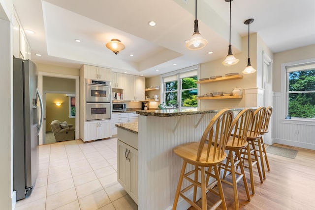 23 Crowell Ln, Tisbury, MA 02568 - kitchen featuring stainless steel appliances, open shelves, healthy amount of natural light, a kitchen bar, and wainscoting