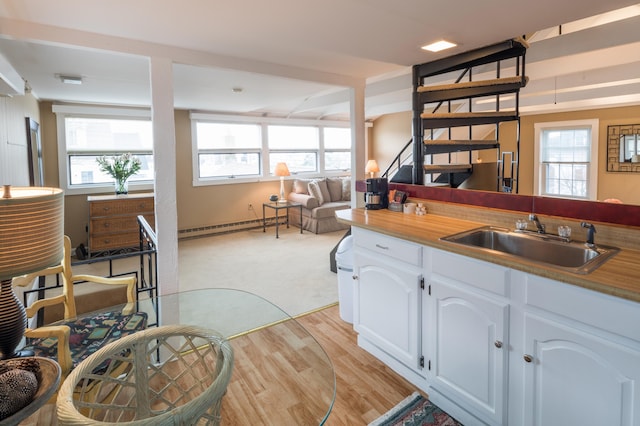 44 Commercial St, Provincetown, MA 02657 - kitchen with a sink, a baseboard radiator, white cabinetry, open floor plan, and light wood-style flooring