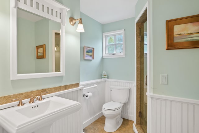 20 James Pond Way, West Tisbury, MA 02575 - bathroom with a wainscoted wall, toilet, a sink, a stall shower, and a decorative wall