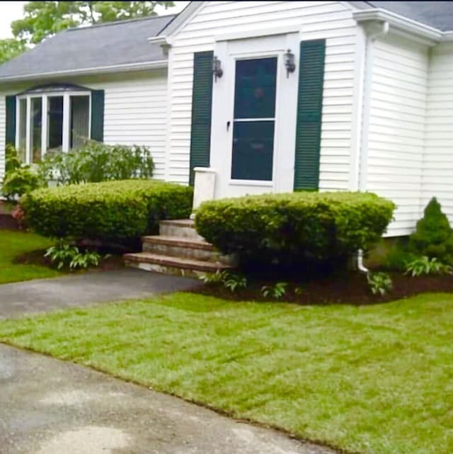 view of exterior entry featuring a lawn