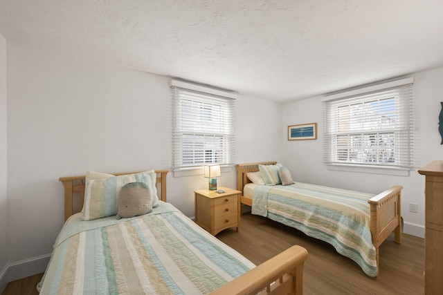 bedroom with wood-type flooring, multiple windows, and a textured ceiling