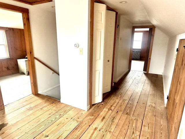 corridor featuring lofted ceiling, light wood-style flooring, plenty of natural light, and radiator heating unit