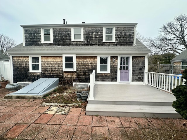 rear view of house with a wooden deck, fence, and a shingled roof