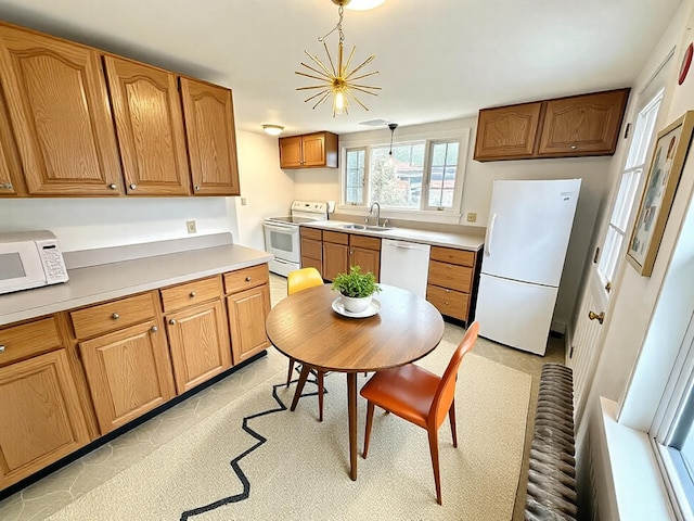 kitchen featuring white appliances, a sink, light countertops, a notable chandelier, and brown cabinets
