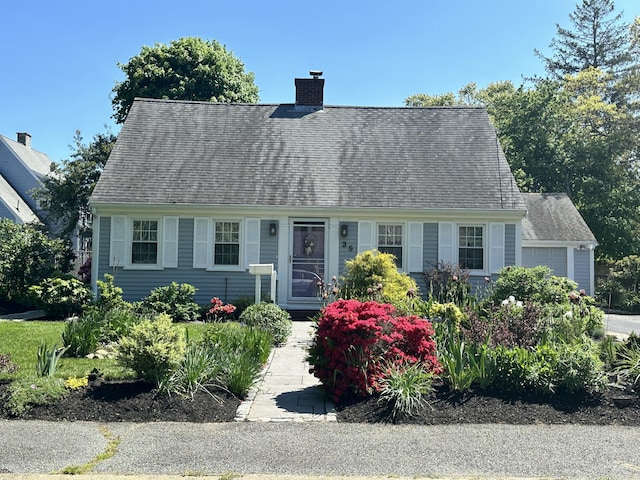cape cod home featuring a garage and a chimney