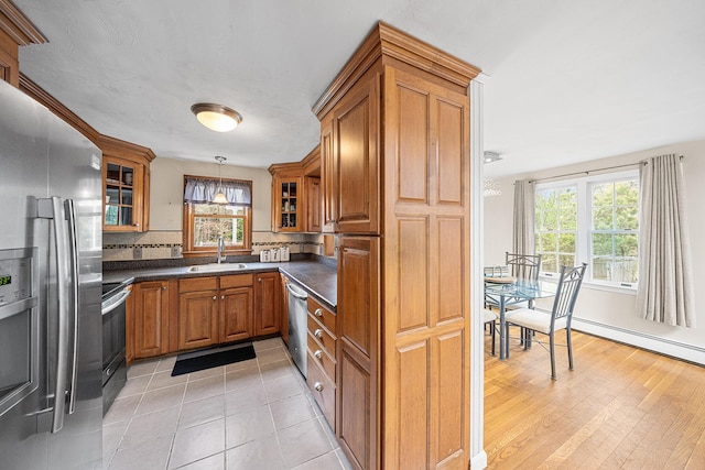 239 Upper County Rd, South Dennis, MA 02660 - kitchen with stainless steel appliances, a sink, brown cabinets, dark countertops, and plenty of natural light