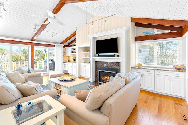 living area with wood ceiling, ceiling fan, a high end fireplace, lofted ceiling with beams, and light wood-style flooring