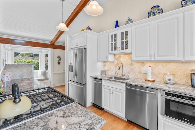 kitchen featuring backsplash, appliances with stainless steel finishes, lofted ceiling with beams, and a sink