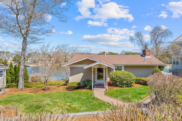 view of front of house with a water view, a chimney, and a front lawn