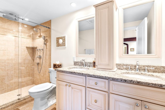 bathroom featuring a sink, a stall shower, toilet, and double vanity