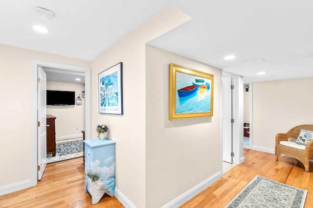 hallway featuring baseboards, recessed lighting, and light wood finished floors