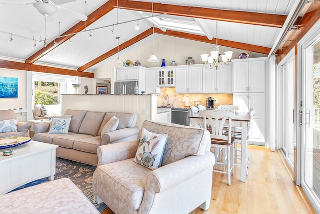 living room with a chandelier, vaulted ceiling with beams, and light wood-type flooring