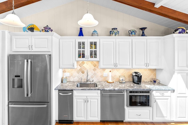 kitchen with white cabinets, appliances with stainless steel finishes, lofted ceiling with beams, and a sink