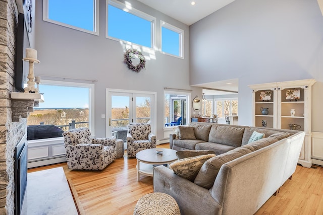 living area with a fireplace, light wood-type flooring, and a baseboard heating unit