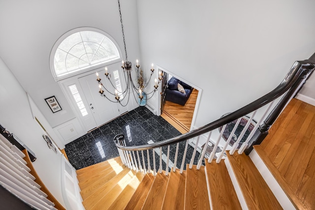 foyer entrance featuring a notable chandelier, stairs, a high ceiling, and wood finished floors