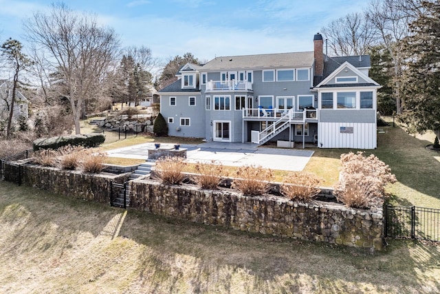 rear view of house featuring fence, a balcony, a chimney, and a patio area