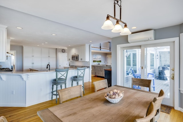 dining area with an AC wall unit, recessed lighting, and light wood finished floors