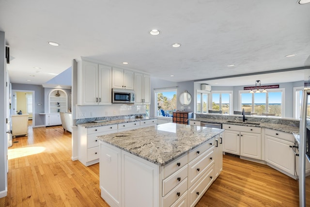 kitchen with light wood finished floors, appliances with stainless steel finishes, a center island, and a sink