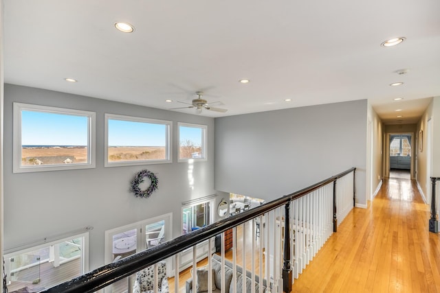 hallway featuring an upstairs landing, recessed lighting, light wood-style flooring, and baseboards