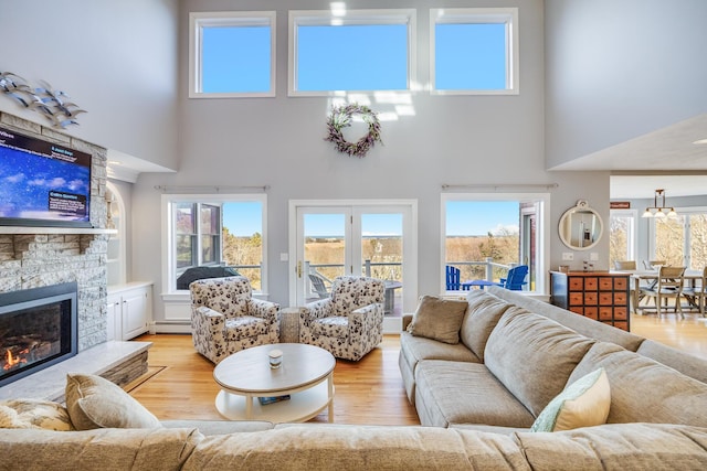 living room featuring baseboard heating, light wood-style flooring, and a fireplace