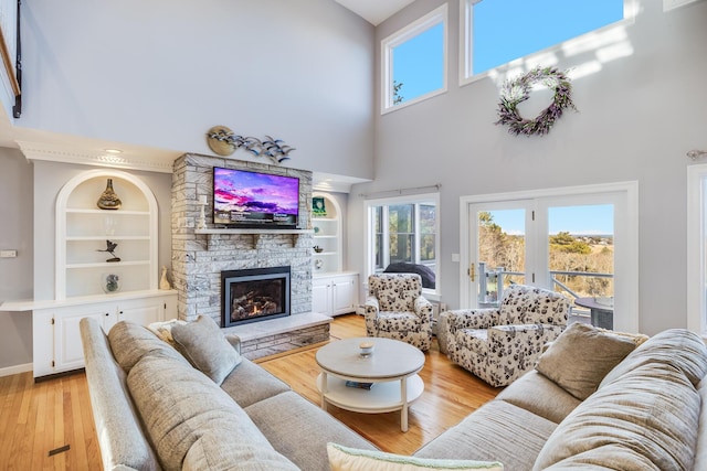 living room featuring light wood-style flooring, built in shelves, a fireplace, and baseboards