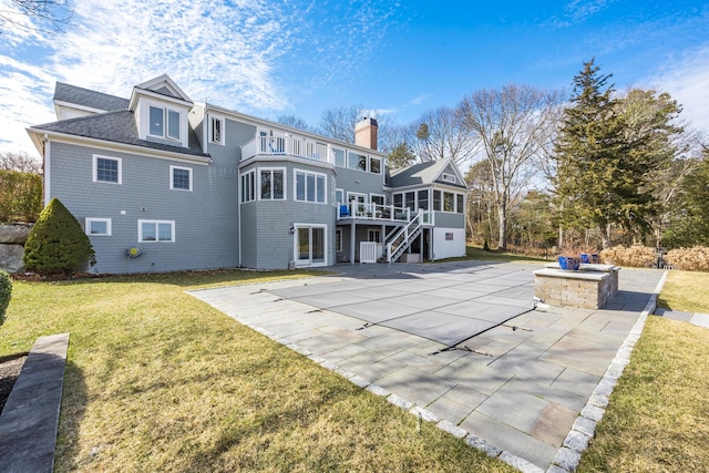 back of house with a lawn, a sunroom, a balcony, stairs, and a patio area