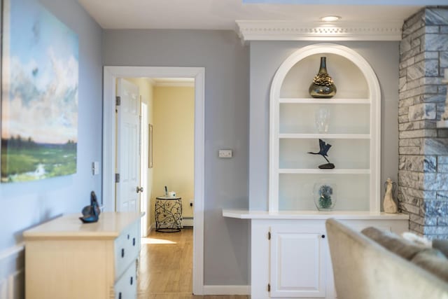 hallway featuring built in features, light wood-style flooring, a baseboard heating unit, and baseboards