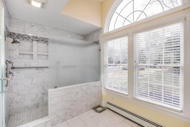 full bathroom with a tile shower, marble finish floor, a baseboard heating unit, and a wealth of natural light