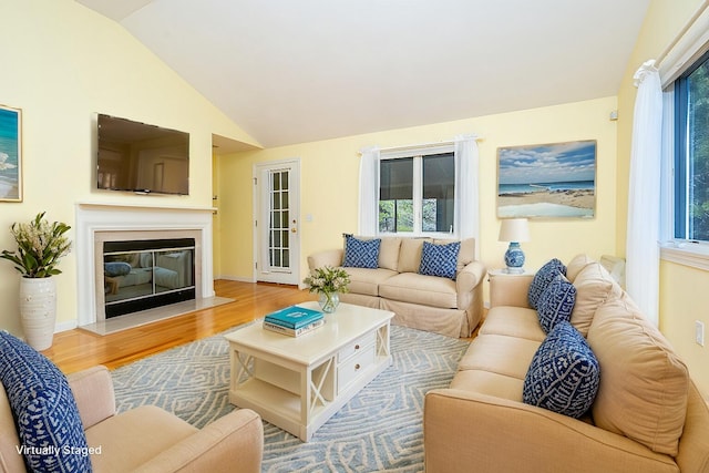 115 Pine Hill Blvd, Mashpee, MA 02649 - living room featuring wood finished floors, vaulted ceiling, plenty of natural light, and a glass covered fireplace