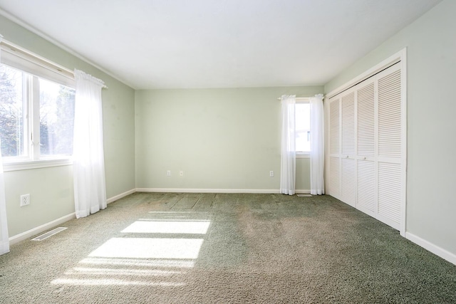 unfurnished bedroom with a closet, visible vents, carpet flooring, and baseboards