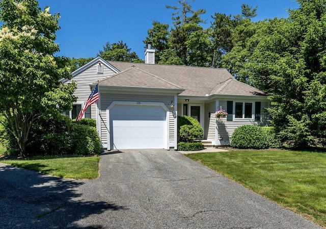 ranch-style home with aphalt driveway, a shingled roof, a front yard, an attached garage, and a chimney