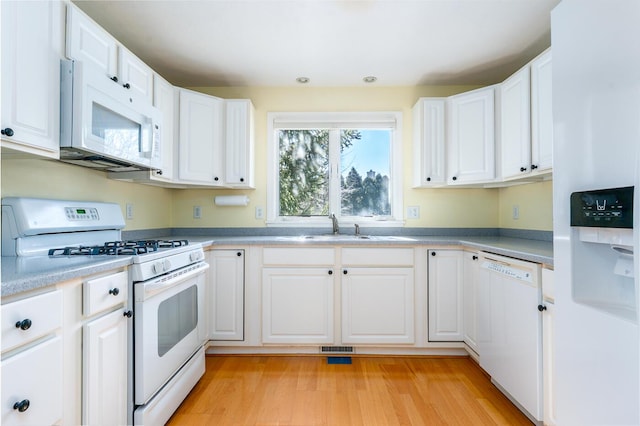 kitchen featuring a sink, white appliances, light wood-style floors, and white cabinetry