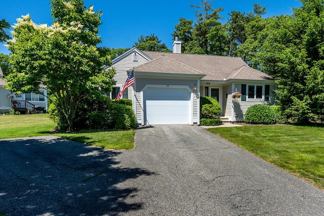 ranch-style home featuring a front lawn, roof with shingles, a chimney, a garage, and driveway