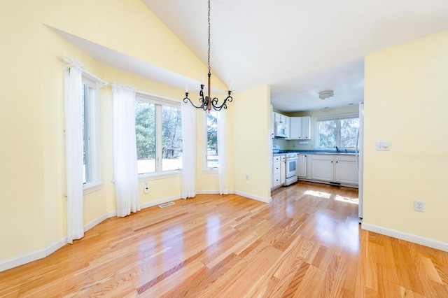 unfurnished dining area featuring light wood finished floors, visible vents, baseboards, a chandelier, and vaulted ceiling