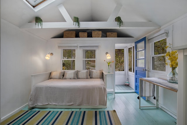 bedroom with hardwood / wood-style flooring, vaulted ceiling with skylight, and a decorative wall