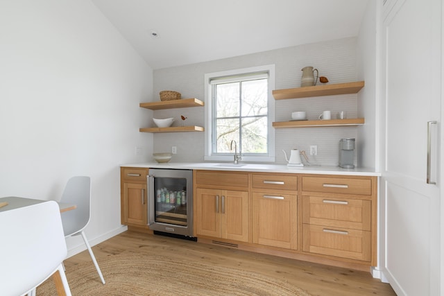 bar featuring sink, backsplash, light wood-type flooring, and wine cooler