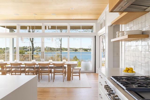 dining room featuring a water view, light hardwood / wood-style flooring, and wooden ceiling