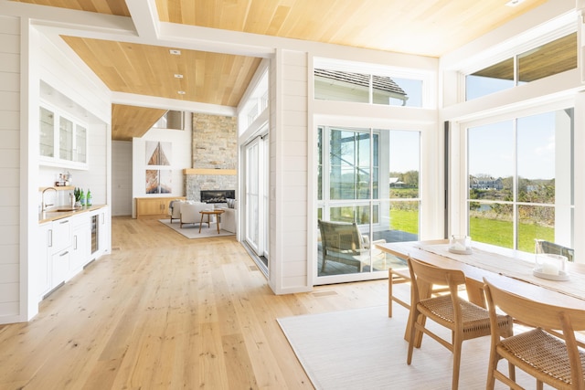 sunroom with sink, wood ceiling, beverage cooler, and a fireplace