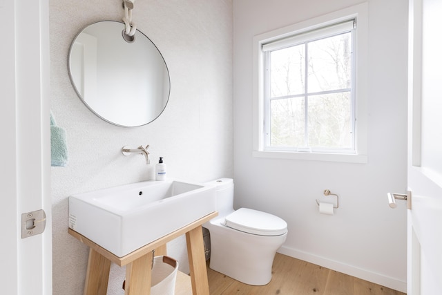 bathroom featuring plenty of natural light, wood-type flooring, and toilet