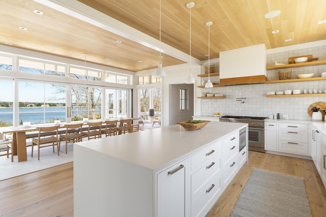 kitchen featuring wooden ceiling, a water view, high end stainless steel range oven, and white cabinetry