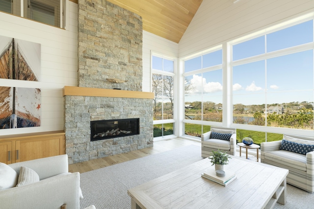 sunroom with wood ceiling, vaulted ceiling, and a stone fireplace