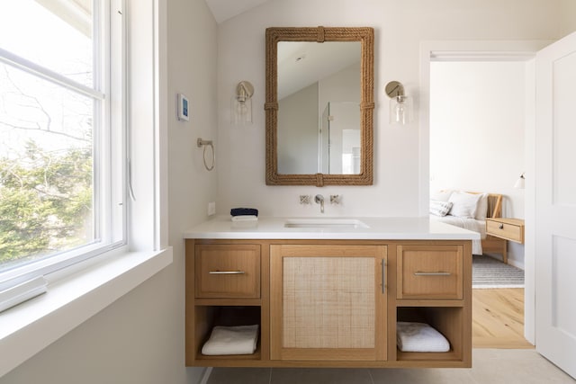 bathroom with tile patterned floors, vanity, and vaulted ceiling