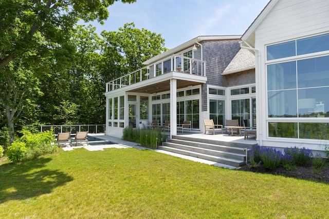 back of property featuring a balcony, a patio, and a lawn