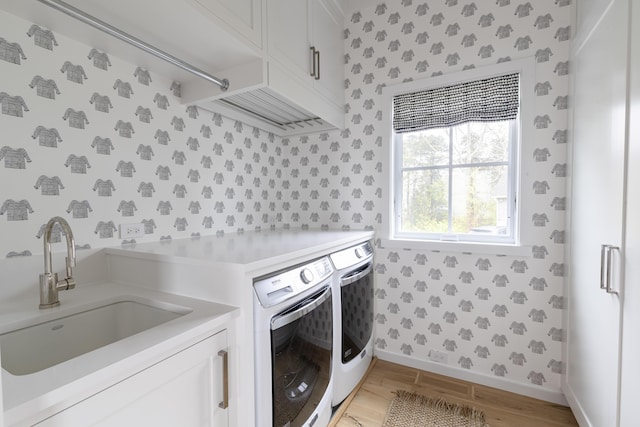 laundry room with washer and dryer, cabinets, sink, and light hardwood / wood-style floors