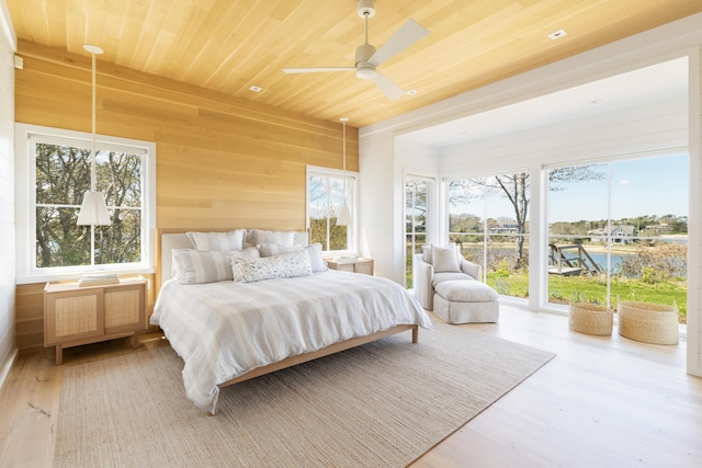 bedroom with ceiling fan, access to outside, hardwood / wood-style flooring, wood ceiling, and wood walls