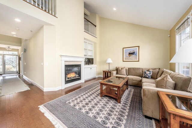 living area with baseboards, a glass covered fireplace, wood finished floors, and plenty of natural light