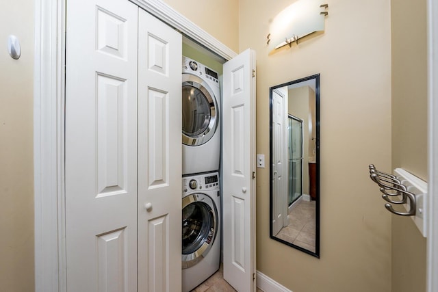 laundry room with baseboards, stacked washing maching and dryer, light tile patterned floors, and laundry area