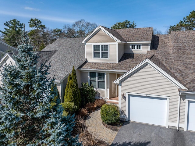 view of front facade featuring aphalt driveway, roof with shingles, and a garage