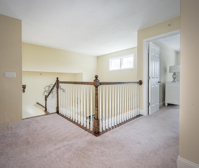 hallway featuring an upstairs landing, baseboards, and carpet floors