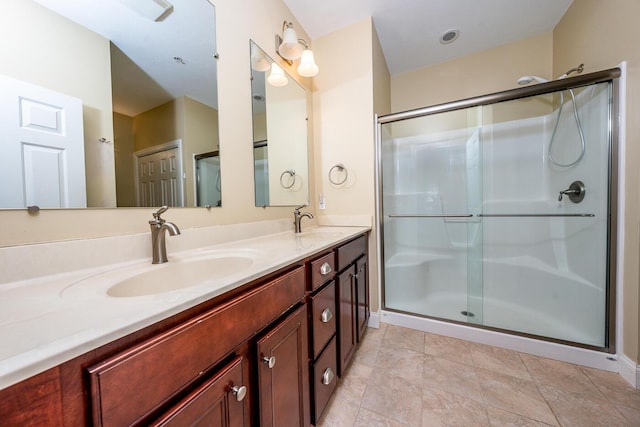 full bath featuring double vanity, a stall shower, and a sink